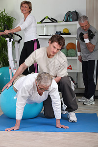 老年人在健身房和私人教练员一起工作图片