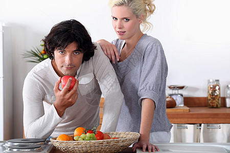 一对夫妇在厨房的厨房里 男人正在吃苹果图片