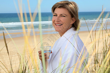 在海滩上喝杯水的女人图片