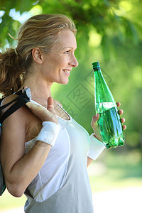 一个微笑的女运动员拿着一瓶酒图片