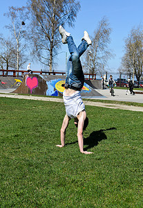 断路器在草地上翻转杂技公园平衡舞蹈演员牛仔裤体操男人运动霹雳舞者图片