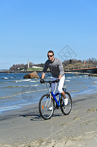 海边骑自行车的英俊男男子肖像运动闲暇海滩海岸海洋男人速度男性支撑假期图片