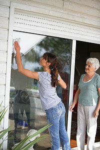 妇女为一位年长女士打扫玻璃庭院门图片