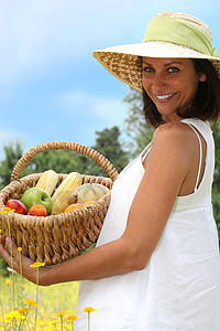一位以水果篮子配菜的妇女的肖像香蕉花朵树木蓝色场地晴天微笑绿色食物女士背景图片