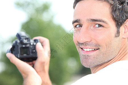 男人看着数码相机的背面图片