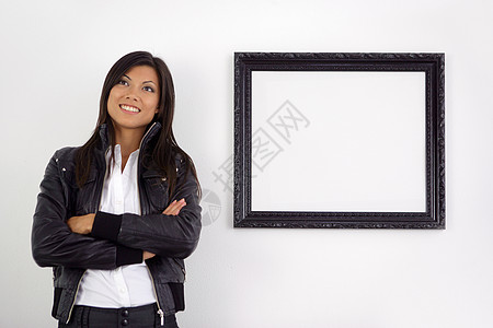 年轻妇女站在空的图片框旁图片