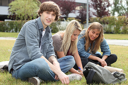 三个学生坐在一个校园的草地上图片