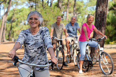 高级妇女及其朋友骑自行车横穿农村的乡村高清图片