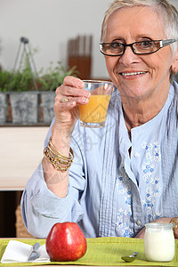 高级妇女吃早餐营养绣花果汁生活手表手镯头发眼镜白衬衫乳白色背景图片