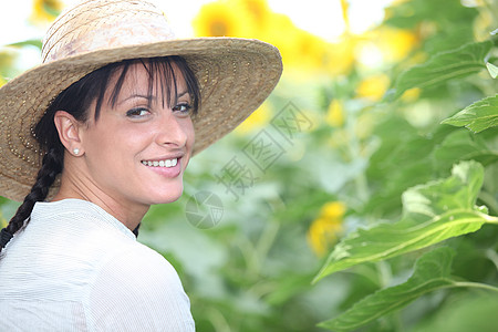 在向日葵田的草帽女人微笑帽子场地稻草植物女性环境叶子绿色花朵图片