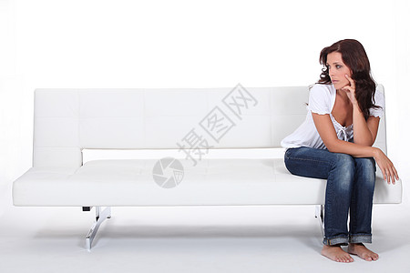 美丽的女人坐在沙发上寂寞朋友孤独服装师长椅赤脚时装房间女性设计师图片