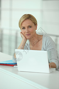 拥有计算机的金发女人家具灰色屏幕办公室笔记本地毯电话工作女性化窗户图片