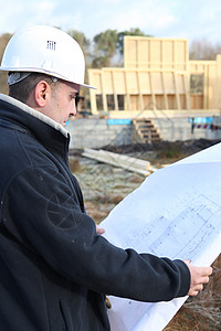 建筑师站在木屋框架旁图片