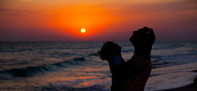 母亲和小儿子的背影海洋天空男生海岸橙子家庭地平线喜悦女士支撑图片