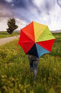 带雨伞的女孩在田地与戏剧天空图片
