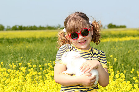 在黄田里养着兔子宠物的小女孩图片