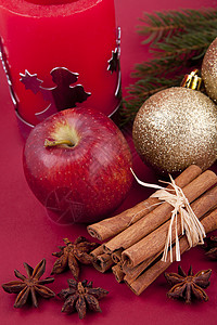 圣诞苹果蜡烛圣诞装饰红苹果 肉桂 香肠和红底树装饰品宏观季节香气假期火花金子星星八角食物背景