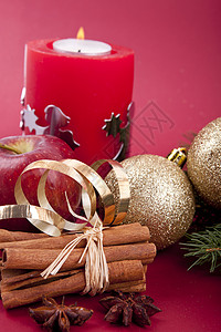 圣诞苹果蜡烛圣诞装饰红苹果 肉桂 香肠和红底树火花星星庆典季节蜡烛食物芳香假期丝带香料背景