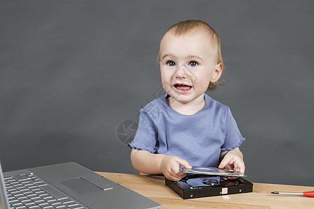在开放式硬盘中工作的儿童磁盘桌子螺丝刀计算机螺丝钳子乐器部分婴儿背景图片