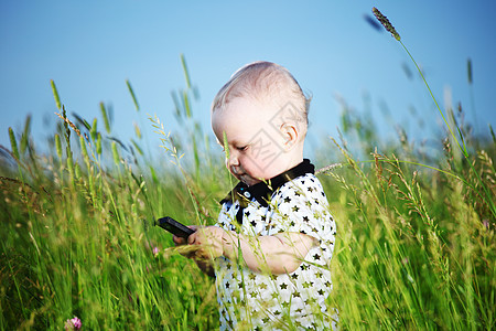 男孩在草地上打来电话技术喜悦场地男性讲话眼睛头发木头童年微笑图片