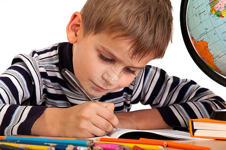 可爱的男生在写字桌子学校地球童年计算器学生学习小学生教科书写作图片