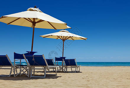 沙滩上伞下椅子的甲板椅天空阳光休息室旅游甲板地平线旅行阴影海滩海洋图片