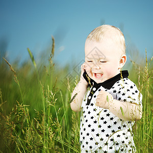男孩在草地上打来电话童年讲话头发蓝色眼睛喜悦儿子天空技术乐趣图片