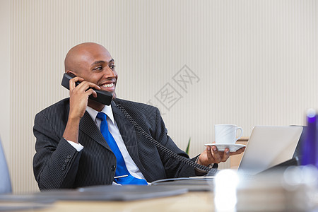 商务人士在喝茶时通过电话交谈图片