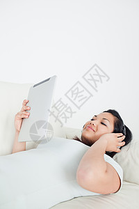 妇女躺在沙发上 戴耳机并保持触觉图片