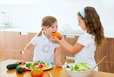 在家厨房准备沙拉的漂亮厨师姐妹孩子们蔬菜黄瓜美食食物烹饪孩子女孩们童年桌子图片