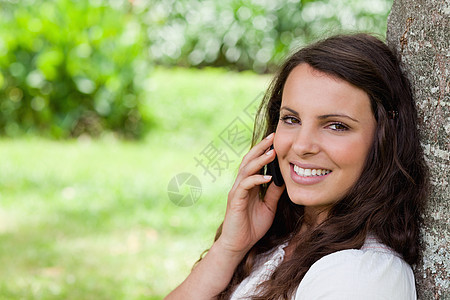 年轻微笑的女士 在电话里说话时看着Ca图片