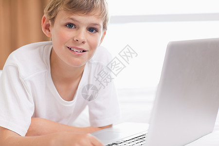 使用笔记本电脑的微笑男孩快乐男孩们娱乐好奇心乐趣外表互联网技术房子冲浪图片