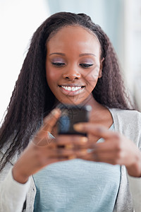 近距离的快乐女人朗读短信机动性细胞微笑技术手机讲话房子客厅闲暇电话图片
