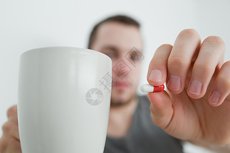 男人展示一粒药片和一杯杯子图片