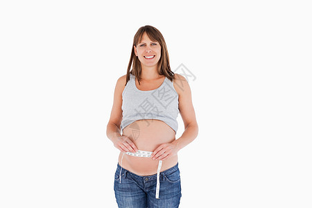 身立时测量肚子的有魅力的怀孕妇女图片