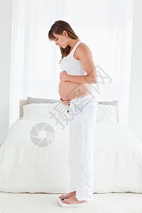 有吸引力的怀孕妇女 在站着时使用比例表图片
