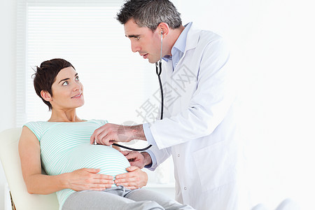 医生用听诊器检查孕妇的腹部图片