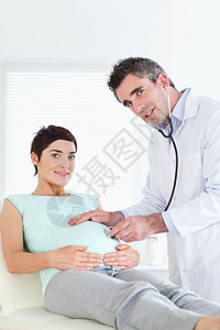 医生用听诊器对孕妇进行检查微笑腹部说谎年轻人肚子女士病人幸福孕产医院图片