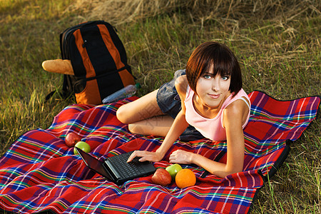 可爱的姑娘在户外休息背包闲暇女孩草地说谎女士水果假期青年野餐图片