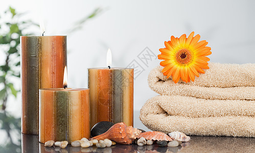 在毛巾和海壳上用橘橙色雪贝拉点燃蜡烛图片