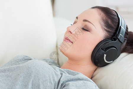 躺在沙发上听音乐的放轻松的女人图片