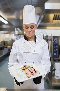 微笑的厨师看着她的盘子柜台烤箱美食餐厅帽子烹饪厨房女士女性制服图片
