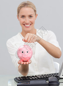 微笑的女商务人士 在猪银行存钱图片
