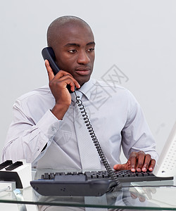 办公室的非裔美洲商务人士通过电话打到办公室幸福桌子笔记本人士微笑团队商务男性经理男人图片