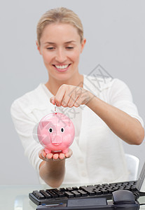 在猪银行存钱的女商务人士图片