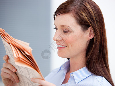 笑笑的女商务人士阅读报纸图片
