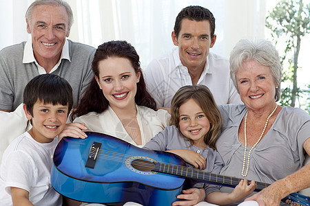 在客厅里拿着吉他的家庭肖像兄弟男生男人母亲乐趣女性夫妻幸福爸爸祖父图片