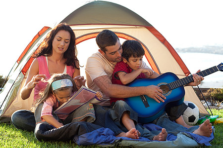幸福的家庭在帐篷里弹吉他图片