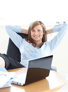 微笑的女商务人士看着笔记本电脑图片