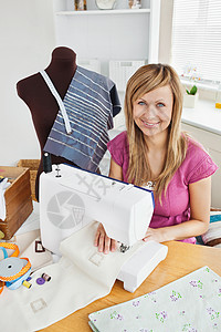 积极的青年妇女在家里缝衣服饰样本测量形式卷尺着装裁缝磁带商务工作缝纫机图片